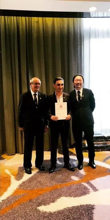 Alper Billik holding his Advanced Sommelier result with two members of the Court