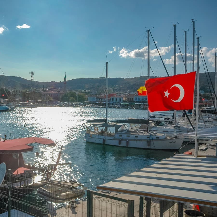 Sailing boats and a Turkish flag in the harbour at Urla, with the town behind